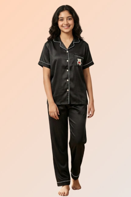 Woman wearing a black cotton brush front-open pajama top with a teddy bear pocket and matching long pants.