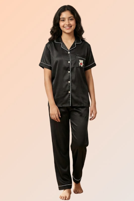 Woman wearing a black cotton brush front-open pajama top with a teddy bear pocket and matching long pants.