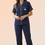Woman lounging in a navy blue cotton brush night suit featuring a front-open shirt with a puppy patch and comfortable long pajama pants.