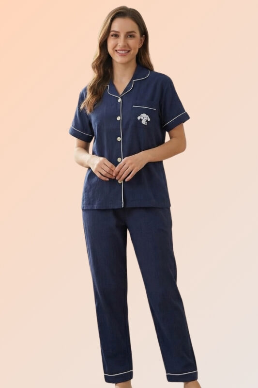 Woman lounging in a navy blue cotton brush night suit featuring a front-open shirt with a puppy patch and comfortable long pajama pants.