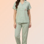 Woman wearing a soothing sage green cotton brush pajama set with a heart pocket shirt and relaxed-fit long pants.