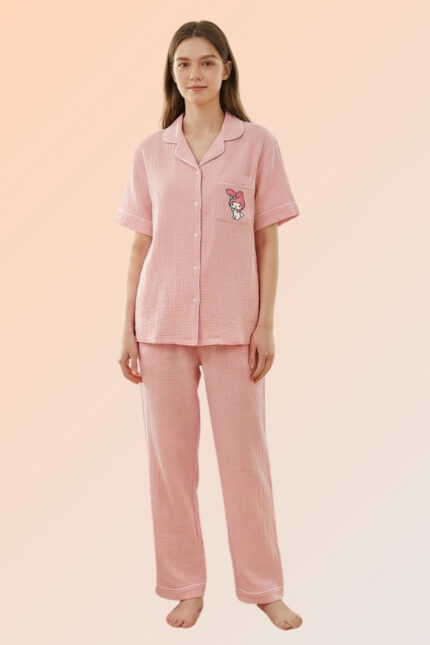 Woman modeling a pretty pink 2-piece nightwear set made of cotton brush, featuring a character pocket shirt and long pajama bottoms.