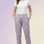 Full-body shot of a model wearing light purple banana print women's pajamas with neon outlines, drawstring with tassels, and hands in pockets.