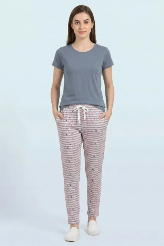 Full-body view of a model in versatile striped and star-sprinkled women's pajamas in grey with small stars, drawstring with tassels, and sneakers.