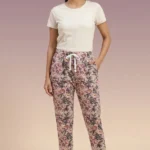 Full-body photo of an Indian woman modeling ornate floral print women's pajamas in tan with pink and purple flowers, featuring pockets and white slippers.