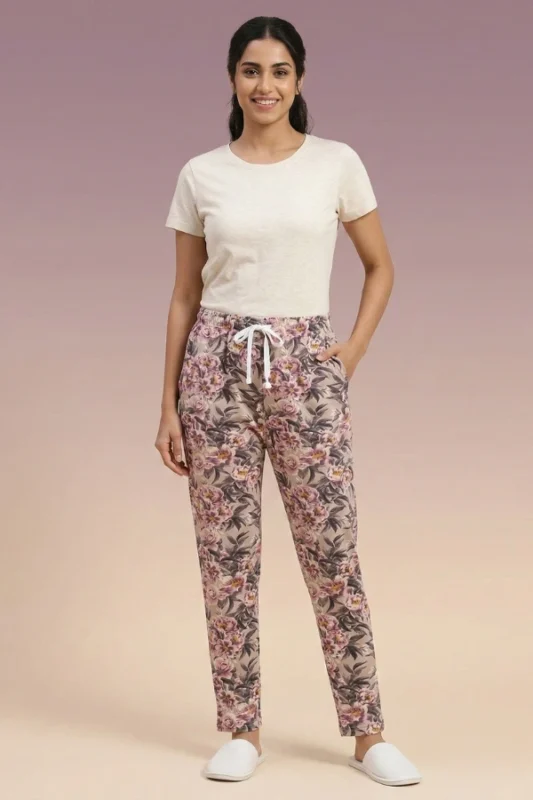 Full-body photo of an Indian woman modeling ornate floral print women's pajamas in tan with pink and purple flowers, featuring pockets and white slippers.