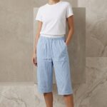 Woman wearing a light blue cotton capri with drawstring waist and white t-shirt.