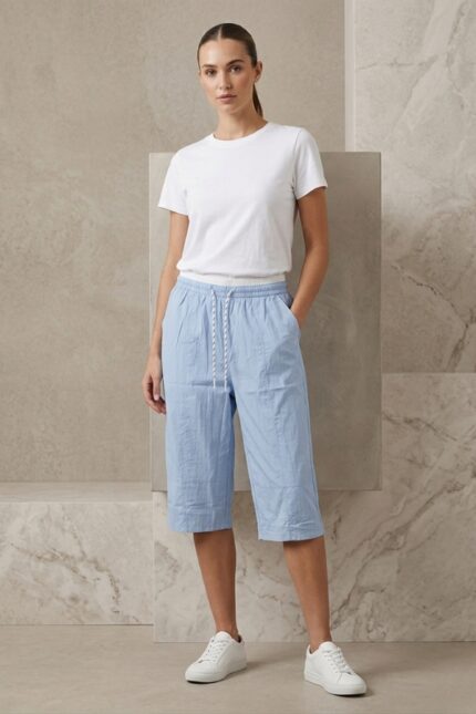 Woman wearing a light blue cotton capri with drawstring waist and white t-shirt.