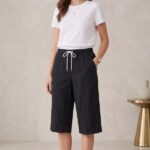 Woman standing casually wearing a solid black cotton capri and a plain white t-shirt.