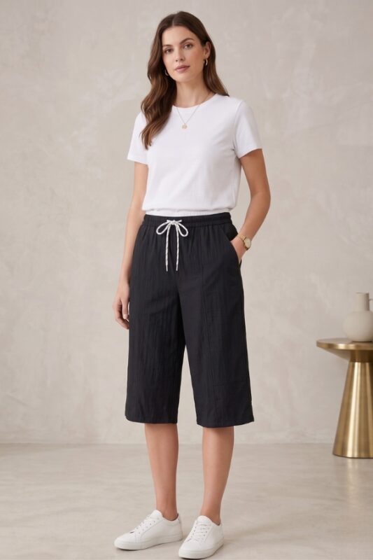 Woman standing casually wearing a solid black cotton capri and a plain white t-shirt.