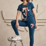 Woman wearing a relaxed fit deep blue cotton t-shirt and pajama set featuring a Mickey Mouse graphic print, standing casually with a vintage camera around her neck.