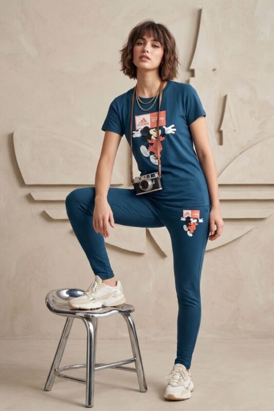 Woman wearing a relaxed fit deep blue cotton t-shirt and pajama set featuring a Mickey Mouse graphic print, standing casually with a vintage camera around her neck.