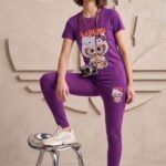 Woman standing casually, wearing a vivid purple cotton t-shirt and pajama pants set with a cute Labubu graphic on the front.