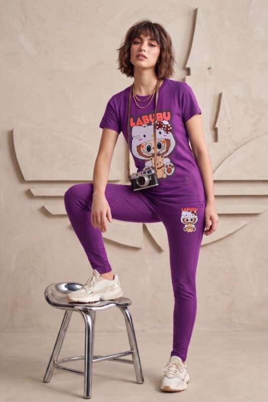 Woman standing casually, wearing a vivid purple cotton t-shirt and pajama pants set with a cute Labubu graphic on the front.