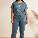 Woman standing in a slate blue relaxed fit cotton pajama set featuring a white floral wreath and the text faith over fear.