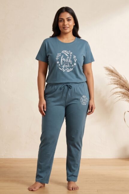 Woman standing in a slate blue relaxed fit cotton pajama set featuring a white floral wreath and the text faith over fear.