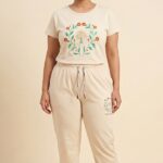 Woman wearing a beige imported cotton pajama set featuring a botanical wreath graphic and the text Find Calm.