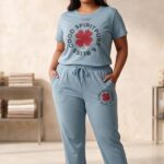 Woman posing in a light blue relaxed fit cotton pajama set featuring a red four-leaf clover and the text Good Spirit Pure & Bliss.