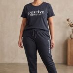 Plus size woman wearing a navy blue relaxed fit cotton pajama set with the words positive mind vibes life printed on the t-shirt.