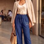 Model posing in royal blue relaxed fit linen pajama pants with a light blazer and handbag.
