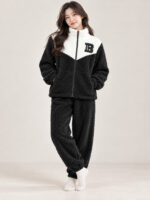 Woman wearing a black and cream plush winter co-ord set with a zip-front top and matching pyjamas