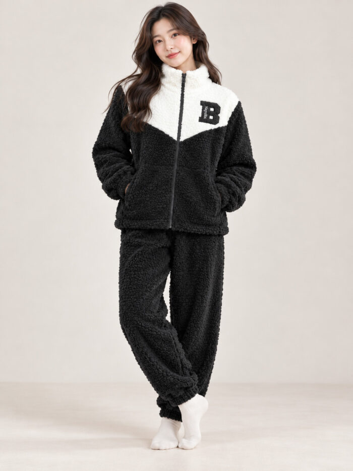 Woman wearing a black and cream plush winter co-ord set with a zip-front top and matching pyjamas