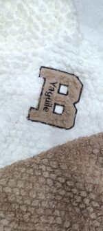 Close-up of the plush textured fabric and letter B chest appliqué on the brown and cream top
