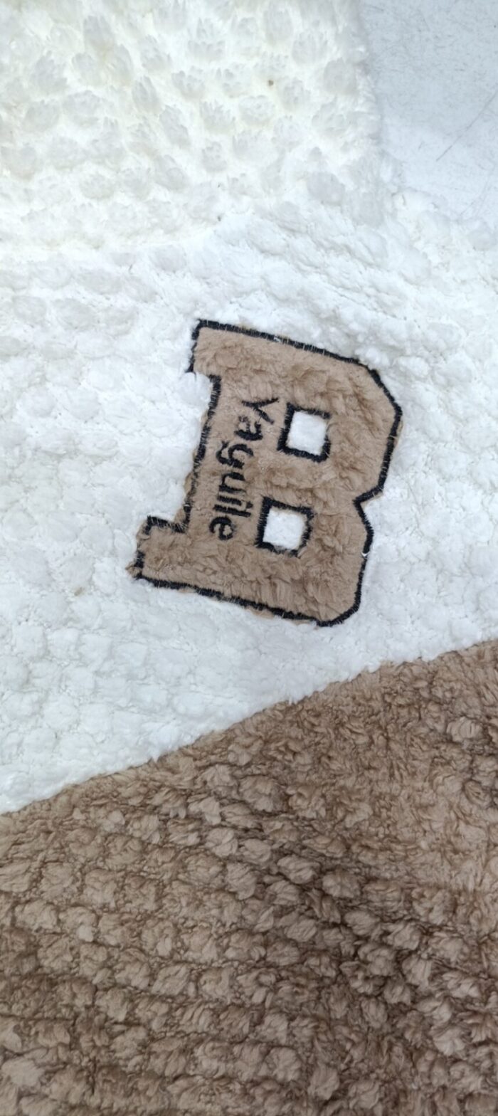 Close-up of the plush textured fabric and letter B chest appliqué on the brown and cream top